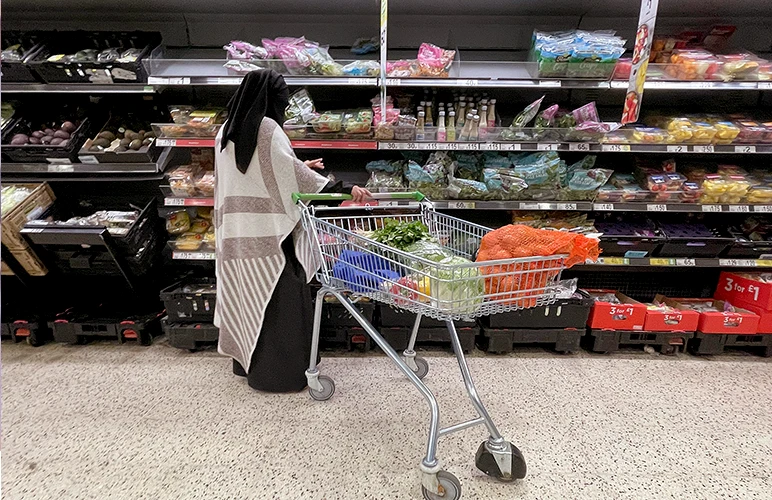 A woman looking at produce on a shelf in an Asda supermarket