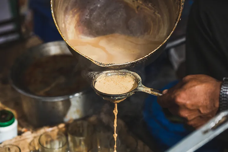 Chai being poured through a sieve