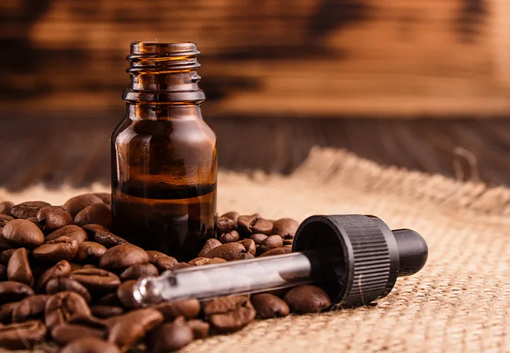 a small container of coffee extract surrounded by coffee beans 