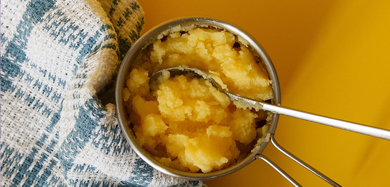 A pot of ghee with a spoon in it and a cloth next to the pot